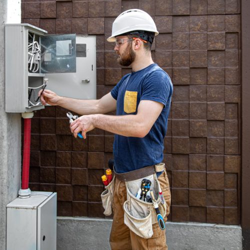 electrician builder work examines cable connection electrical line fuselage industrial switchboard professional overalls with electrician s tool 1